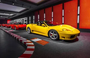 A sports car is displayed on a red and white checkered floor in a modern and stylish showroom with bright lighting