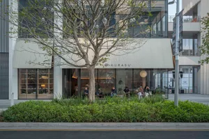 A lively restaurant interior with a tree in the center, surrounded by people, chairs, and dining tables