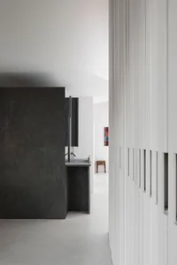Modern kitchen with a black granite countertop, black cabinets, a sink, and refrigerator in a dimly lit space