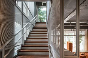 A staircase with a metal railing in a room with a window, surrounded by wood and natural light