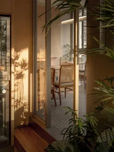 A well-lit living room with a chair, dining table, and potted plant, featuring a comfortable and inviting atmosphere