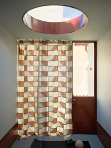 A dimly lit bedroom with a bed in the background and a brown curtain with a patterned design covering the doorway