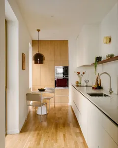 A bright and inviting kitchen and dining area with a predominantly white color scheme, natural light, and modern appliances