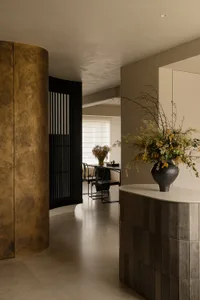 Sophisticated living space with a black and gold color scheme, a large window, a dining table, and a vase with flowers