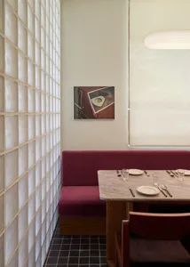 一間充滿光照的餐廳，紫色沙發、餐桌和餐具、掛在桌上的畫作