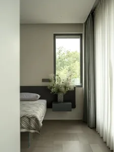 Cozy bedroom with a bed against the wall and a window above it, featuring a black and white color scheme and natural light