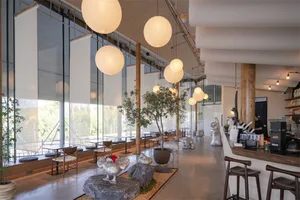 A modern restaurant with a large dining area, decorative elements, and a mix of natural and artificial lighting