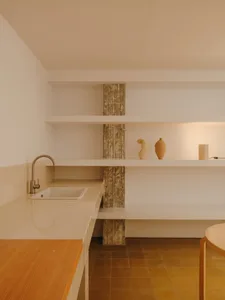 A well-organized kitchen with white cabinets, a tile floor, and wooden shelves, featuring vases and a bowl, with a focus on functionality and simplicity