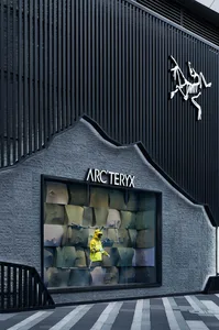 A man in a yellow jacket works on a construction project, installing a glass window in a black and white building