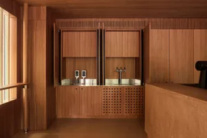 A well-organized kitchen with wooden cabinets, a metal sink, and a brown color scheme, lit by natural light