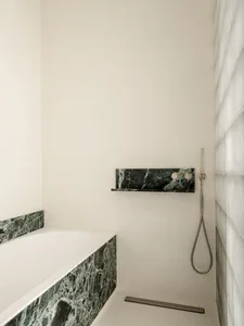 現代浴室內，白色浴缸、淋浴設備和光纖組合磚 countertops，安置在一間清潔線條和簡約設計元素的 dimly lit 空間中