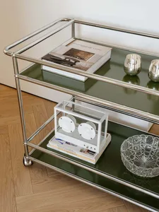 A well-lit living space with a green shelf holding a book, a bowl, and a vase, arranged in a visually appealing manner, with natural light coming in through a window