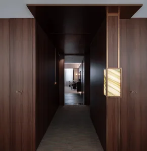 Dark hallway with a wooden surface, carpeted floor, and a doorway at the end