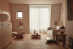 Modern living room with a large window, natural light, a couch, coffee table, chair, and speakers in a clean and organized space with white materials