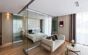 A well-lit living room with a couch, bed, and chair, arranged to maximize space, and a large glass door that brings in natural light