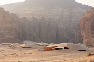 A desert landscape with a mountain in the background, featuring several tents of varying sizes and angles, creating a sense of depth and complexity
