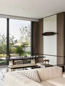 A modern living room with a dining table and chairs, natural light, and comfortable furniture, decorated with books, vases, and bowls