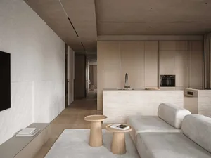 A modern living room with a white couch, dining table, kitchen area, wooden coffee table, and chair, decorated with books and a vase, in a predominantly white space with a bright and airy feel