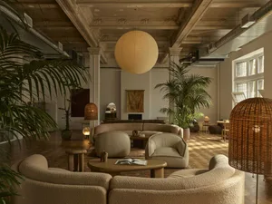 A well-lit living room with a white couch, chair, dining table, and potted plants, creating a comfortable and inviting atmosphere