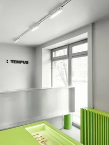 A modern lobby with a green and white color scheme, featuring a large window, a desk, and a bench, with green and white tiles on the walls and floor