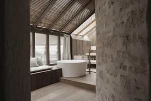 Dimly lit bathroom with a white bathtub, wooden accents, and a sink to the right of the bathtub