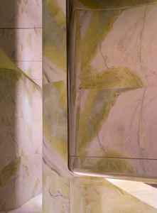 A marble-clad wall in a modern room with soft, diffused lighting and a sophisticated atmosphere