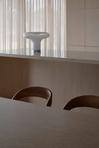 Cozy kitchen with wooden floors, a wooden table, and chairs, featuring a sink, counter, and window in a dimly lit space