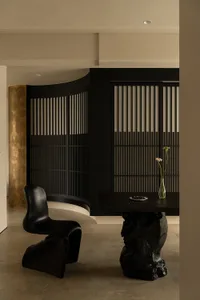 一間現代的生活空間，擺放著一把黑色的椅子、餐桌和一盆花，背景是黑白色彩色
