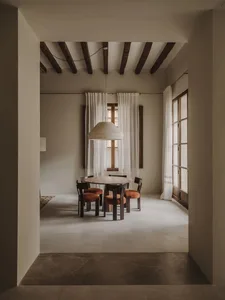 A dimly lit dining room with a wooden table and chairs, surrounded by other furniture, creating a cozy atmosphere