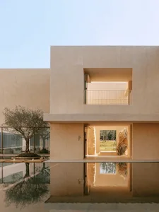 Large modern building with a glass wall, concrete exterior, and open interior space with a large window