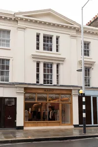 A classical building with a wooden storefront, brick facade, and elegant interior with mannequins on display