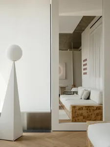 A modern living room with a white couch and chair, surrounded by white walls and soft, diffused lighting, creating a comfortable and inviting atmosphere