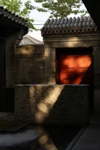 A stone door with an archway and stone wall in the background, set in an outdoor area with natural sunlight creating a warm atmosphere