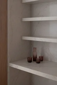 A modern bathroom with a white marble countertop featuring three brown bottles arranged in a neat line, under soft and warm lighting