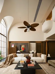 A well-lit living room with a white couch, coffee table, and ceiling fan, creating a comfortable and inviting atmosphere
