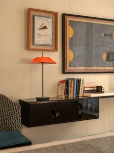 A modern study with a wooden cabinet, chair, bookshelf, and lamp, set against a dimly lit background