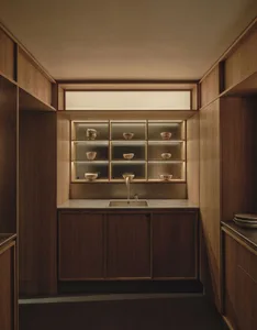 Traditional kitchen with wooden cabinets, a light brown sink, and dim lighting creating a cozy atmosphere