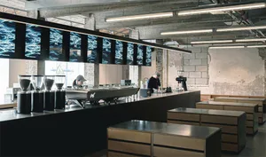Sleek modern kitchen with wooden countertops, appliances, and a large island, lit by bright overhead lighting
