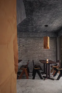 Cozy restaurant interior with a brick wall, stone floor, wooden furniture, and dim lighting