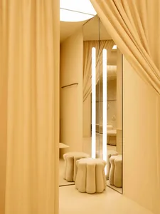 A well-lit dining room with a mirrored surface reflecting the interior, a dining table, and chairs arranged around it