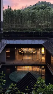 A dimly lit modern room with a pool in the center, surrounded by furniture and decorated with wood and glass materials