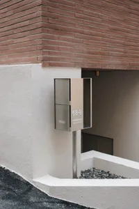 A modern building with a stone exterior and a metal box on the corner, set in an urban environment