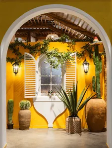 A bright and cheerful bathroom with a yellow wall, a white door, a sink, a window, and a potted plant, with two vases and a clean and inviting atmosphere