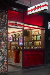 A modern bookstore with a red and white color scheme, featuring wooden chairs and a variety of books on display