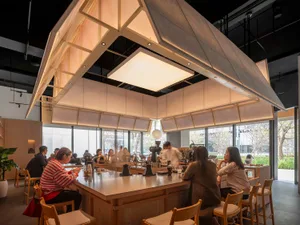 A lively restaurant with a dining table surrounded by chairs, a bar in the background, and people enjoying their time together