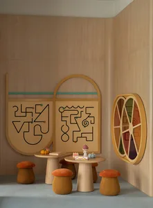 A modern dining room with a wooden table and chairs, set with a cake and oranges, and a mirror on the wall, with natural lighting