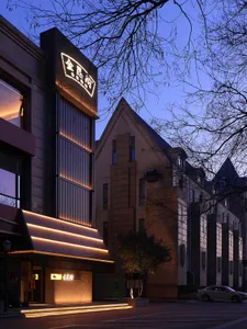 A city building with a brick facade and a prominent archway illuminated by a light source, set against a darker urban backdrop