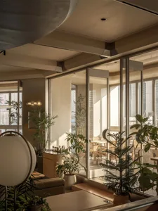 A modern restaurant interior with natural light, potted plants, and comfortable seating areas