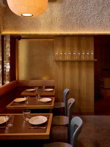 Cozy modern restaurant interior with wooden tables, chairs, and wine glasses, dim lighting creating an intimate atmosphere