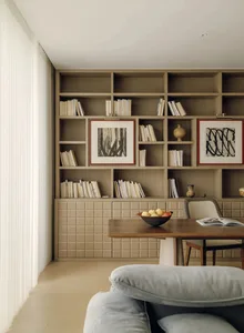 A well-lit living room with a wooden table and chairs, surrounded by books, creating a cozy and intellectual atmosphere